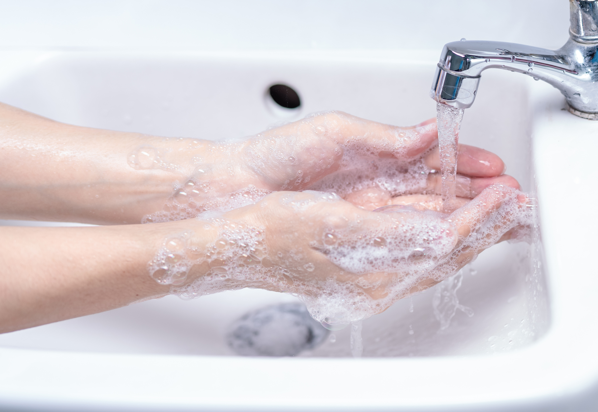 Na tym obrazku widzimy ręce osoby w trakcie mycia w łazience. Jest to ważny krok w zachowaniu higieny osobistej i zapobieganiu rozprzestrzenianiu się zarazków.Osoba trzyma ręce pod strumieniem ciepłej wody. Możemy zauważyć, że używa mydła, które tworzy gęstą pianę. Osoba starannie myje zarówno dłonie, jak i nadgarstki, docierając do wszystkich ich powierzchni